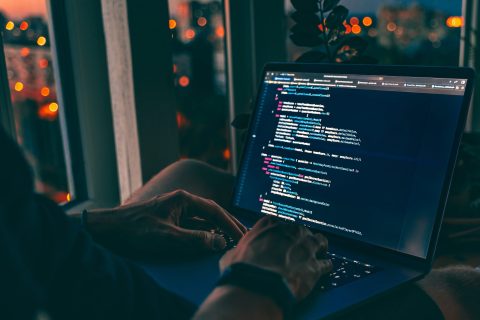 Programmatore di Informatica intento a scrivere codice sul suo computer portatile. Si sta preparando con la scuola online per diplomarsi in Informatica e Telecomunicazioni.